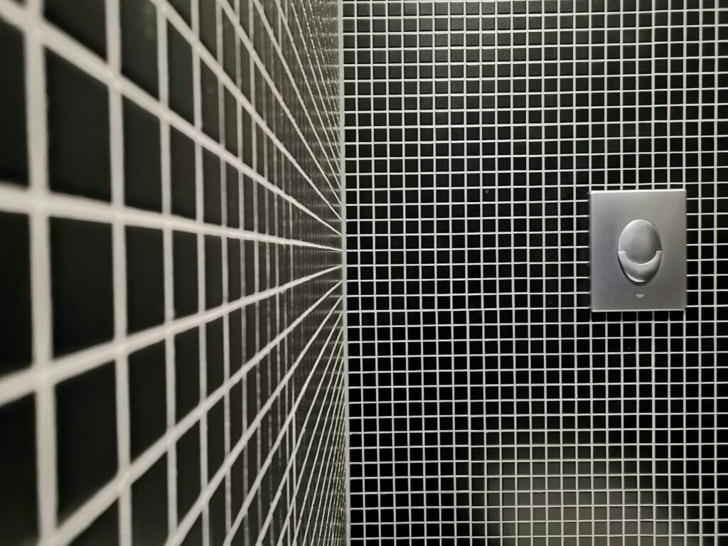a black and white tiled bathroom with a toilet paper dispenser